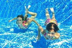 two girls swimming in a blue pool two girls swimming in a blue pool