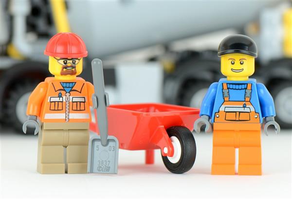 Two LEGO men standing next to a wheelbarrow 
