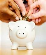 Picture of several hands putting coins into a ceramic pink Piggy bank 