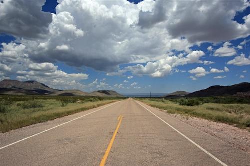 empty highway with big white clouds overhead 