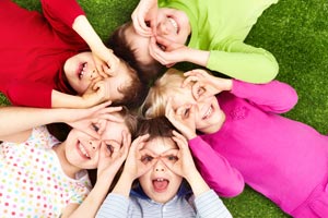 Children lying on grass looking up at sky