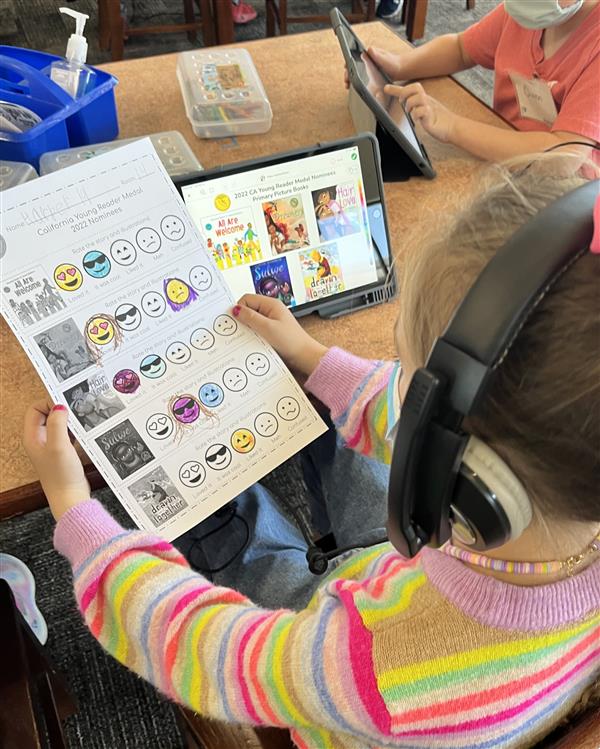 Student is reviewing a worksheet where they have reviewed books, then voting using the Seesaw App