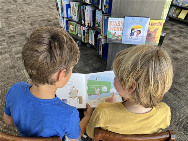 The back of two children reading a book together
